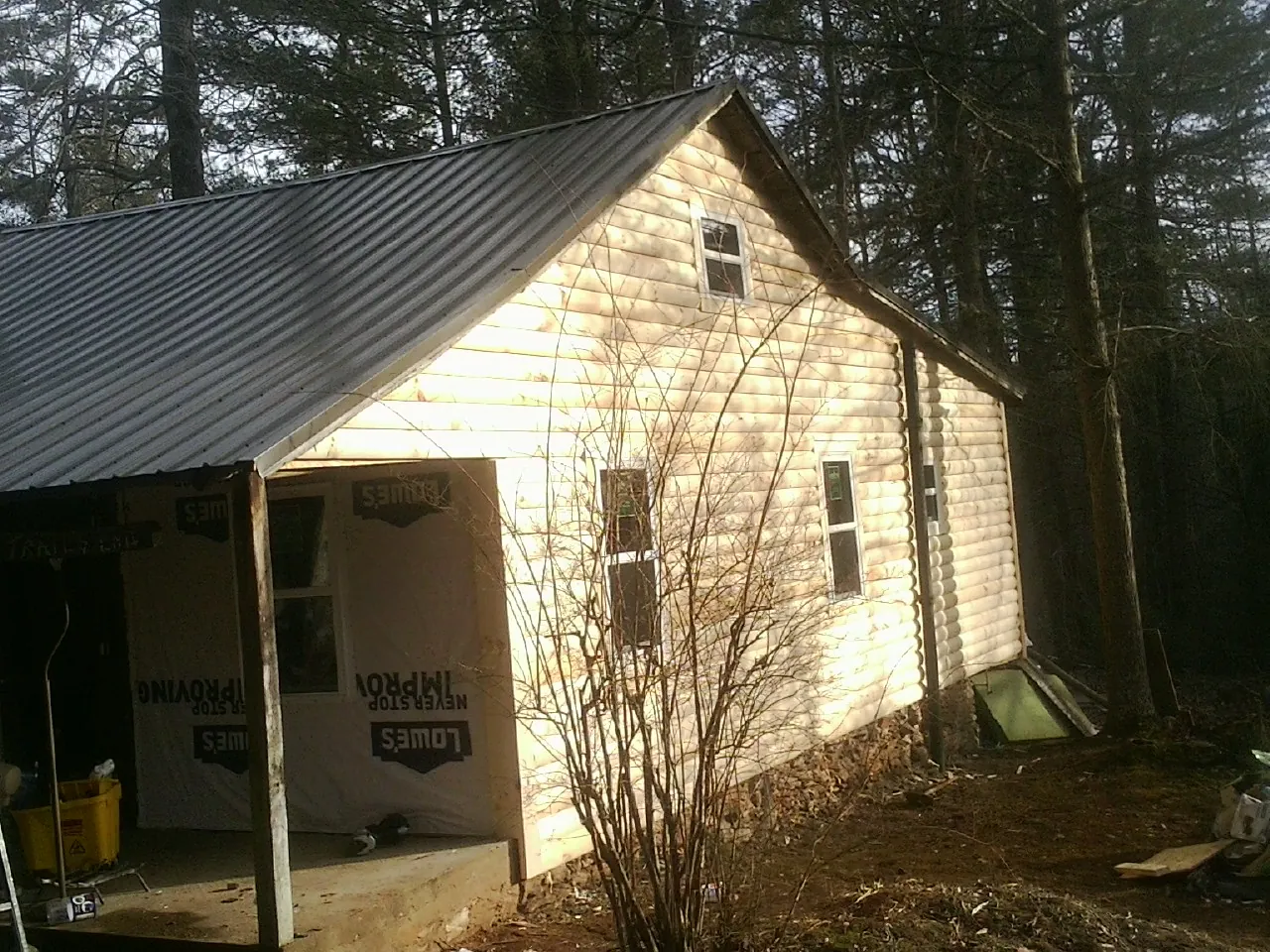 Log siding gable end under a dark metal roof edge in Bosler