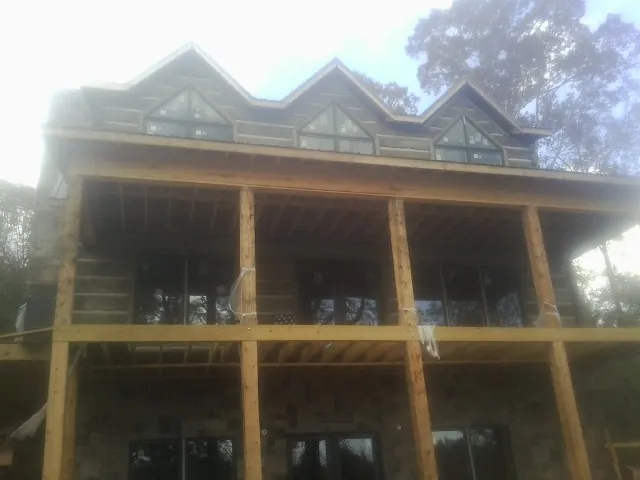 Dormers and porch framing on a large log home under construction — Roof Coating work by our crew in Bosler