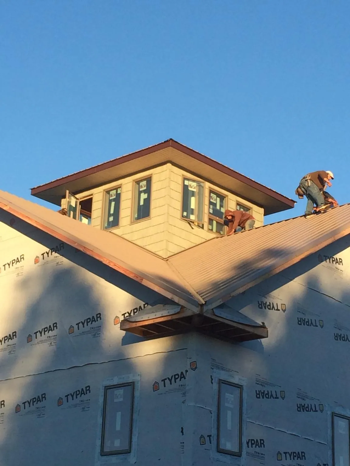 Roofers working around a rooftop cupola on a new metal roof at sunset — Roof Waterproofing in Bosler by Roofing Brothers